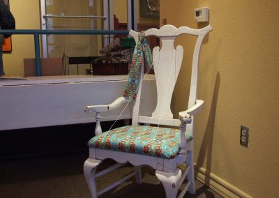 white chair with mendoza's work on the fabric of the seat of the chair