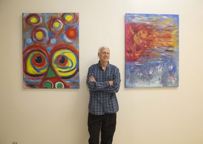 mendoza posing and smiling in front of his paintings