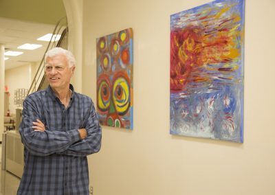 mendoza posing and smiling in front of his painting