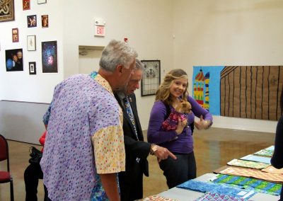 mendoza, a man, and a woman posed with her dog at mendoza's art show