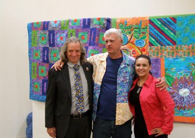 mendoza posed with a man and a woman in front of his artworks