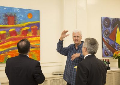 mendoza explaining his artwork with two people observing his art