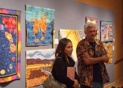 photo of mendoza posing with someone in front of his quilting works