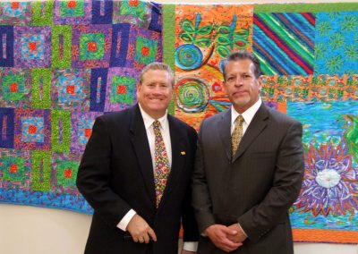 two men posed in front of mendoza's artwork