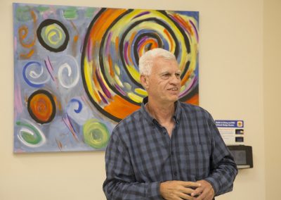 mendoza smiling and speaking in front of his artwork