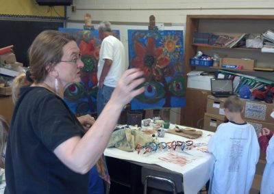 woman standing up while children make artwork