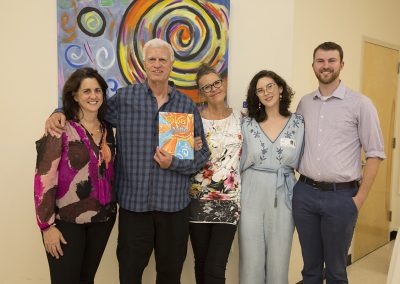 mendoza, holding his book and some people posed in front of his artwork